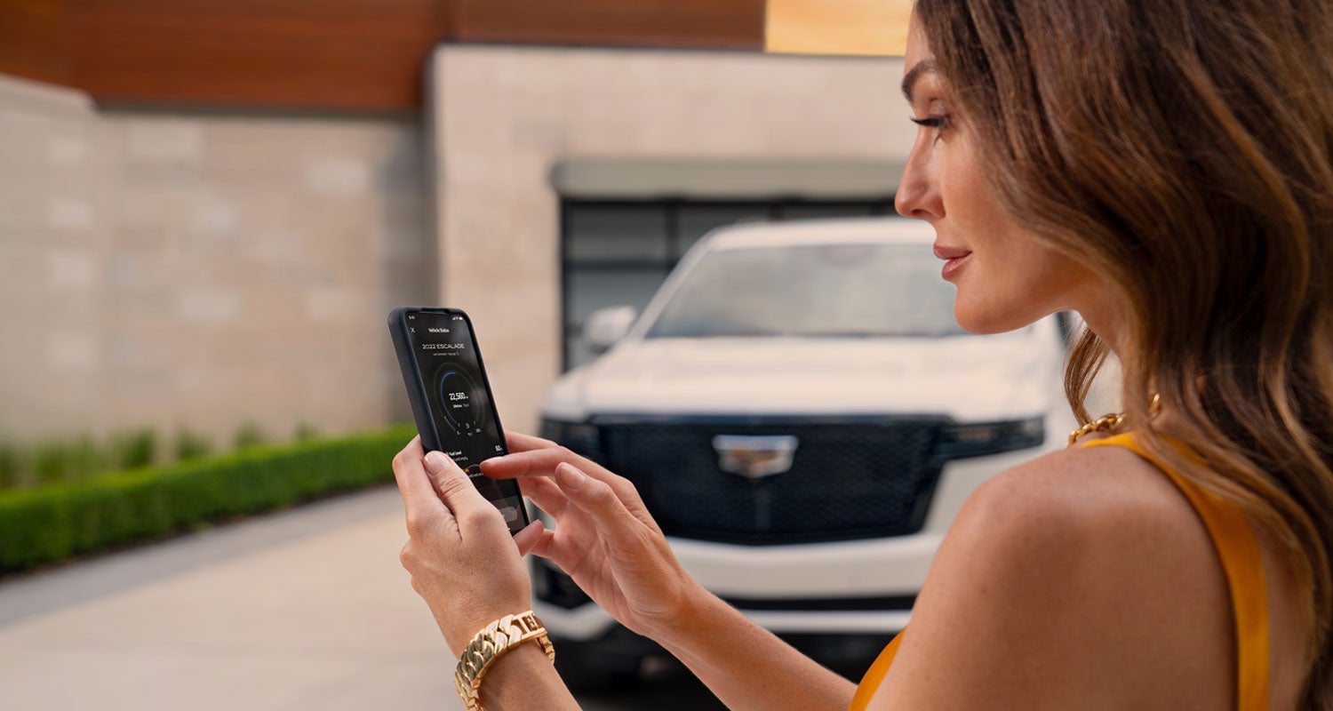 lady checking her mobile with a Cadillac vehicle background | All American Cadillac in MUNCIE IN